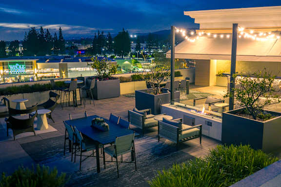 A rooftop patio with tables and chairs is lit up at night.