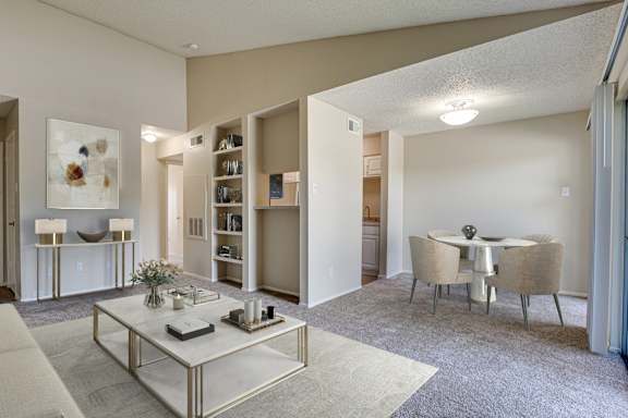 A living room with a white sofa, a coffee table, and a dining table with chairs.