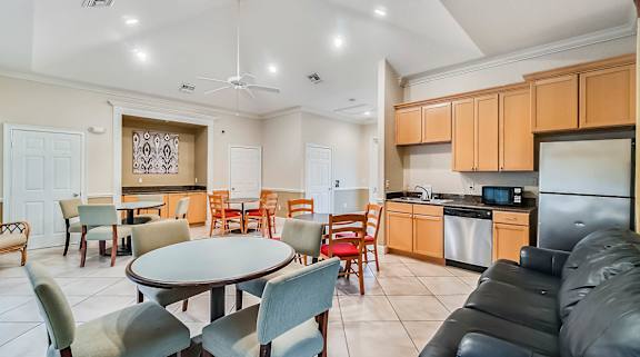 A modern kitchen and dining area with a black leather couch and a round table.