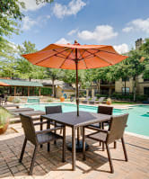 a patio with a table with an umbrella and a swimming pool  at Wind Dance, Texas, 75010