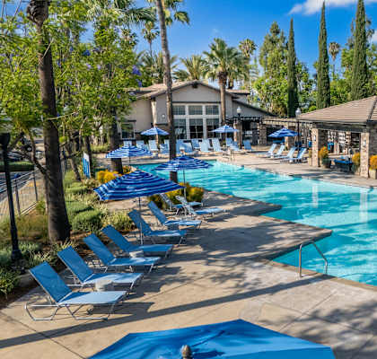 A large swimming pool surrounded by blue lounge chairs and umbrellas.