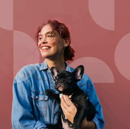 a woman in a denim shirt holding a small black dog