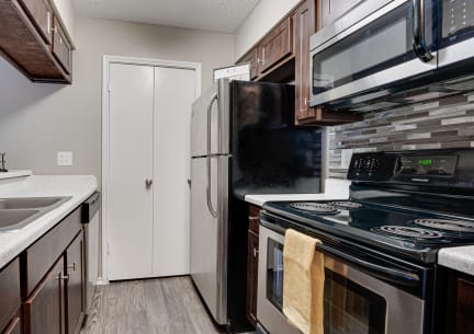 a kitchen with a sink and a refrigerator at The Manhattan Apartments, Dallas, TX, 75252