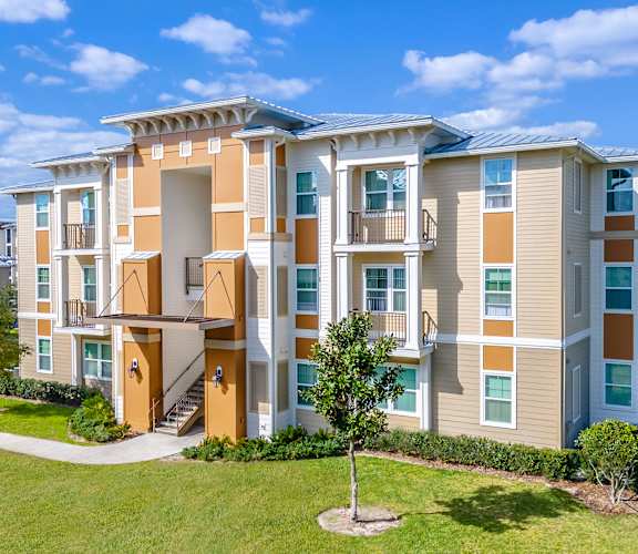 an apartment building with a green lawn and blue sky