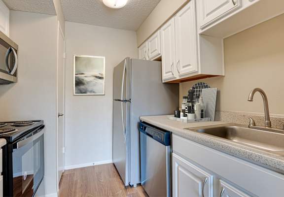 A kitchen with a refrigerator, stove, and dishwasher.
