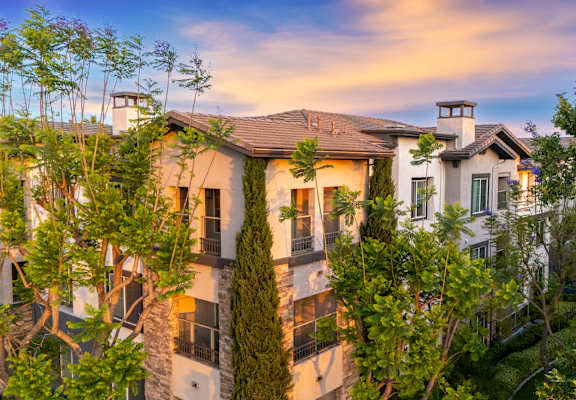 A large house with a balcony is surrounded by trees.