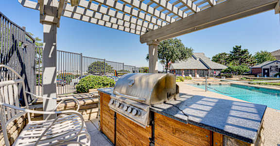A hot tub sits under a pergola on a patio.