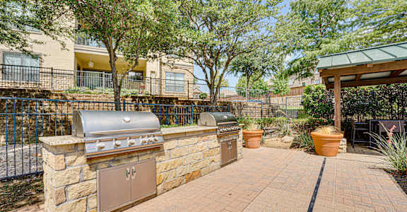 A backyard with a stone wall and a grill.