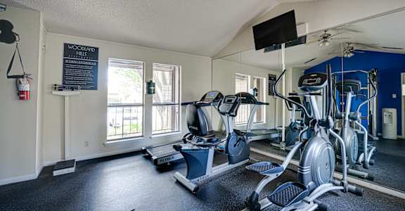 A gym with a variety of exercise equipment including treadmills, stationary bikes, and weight machines.