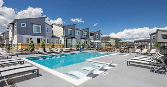 A swimming pool surrounded by lounge chairs and apartment buildings.