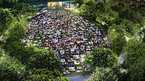 A large crowd of people gathered in a park-like setting for an event.