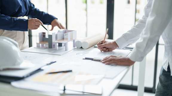 a group of people working on construction plans on a table