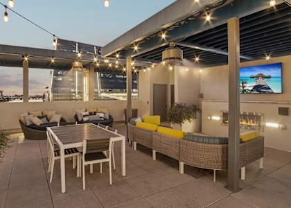 A rooftop patio with a table and chairs under string lights.