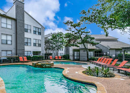 A swimming pool surrounded by a fence and chairs.