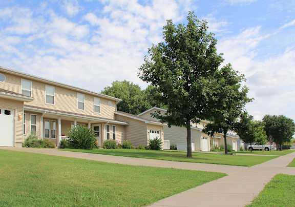 A row of houses with garages and a tree with yellow leaves.
