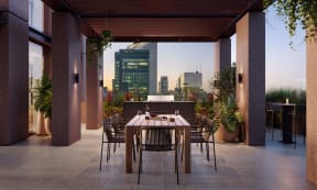 an outdoor dining area with a table and chairs and a city in the background