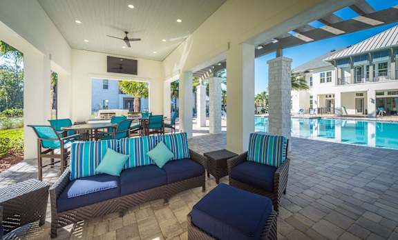 a patio with couches and chairs and a pool in the background at Alaqua Apartments, Florida, 32258
