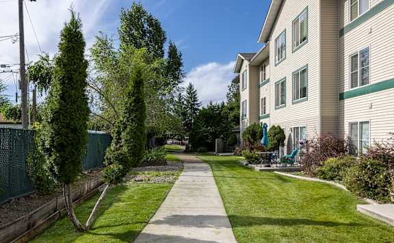 a walkway between two apartment buildings with grass and trees