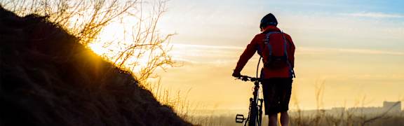 A person riding a bike on a mountain trail during sunset.