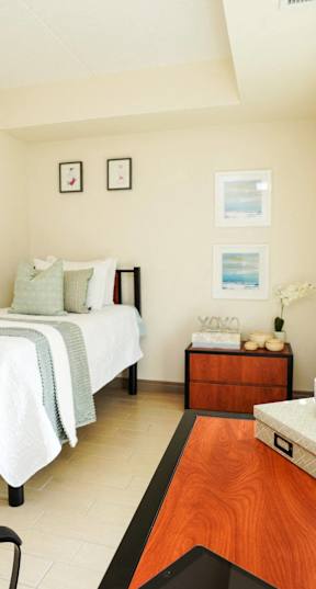 A bedroom with two beds and a nightstand with a lamp.