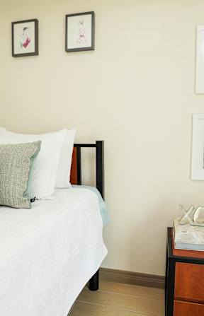 A bedroom with a bed, nightstand, and pictures on the wall.