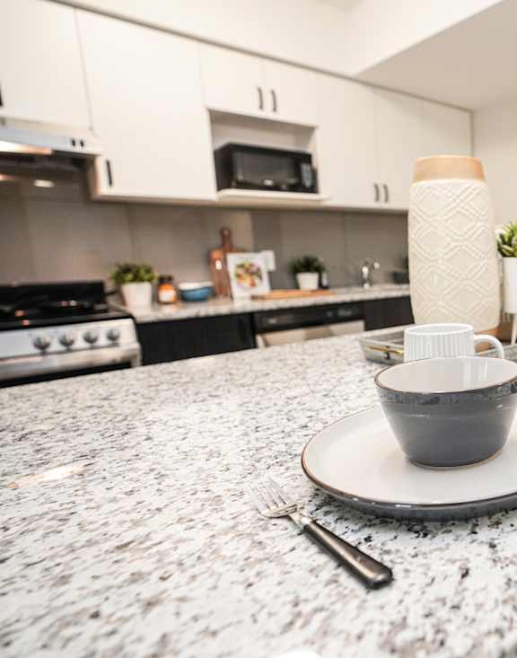 A modern kitchen with a granite countertop and a single chair.