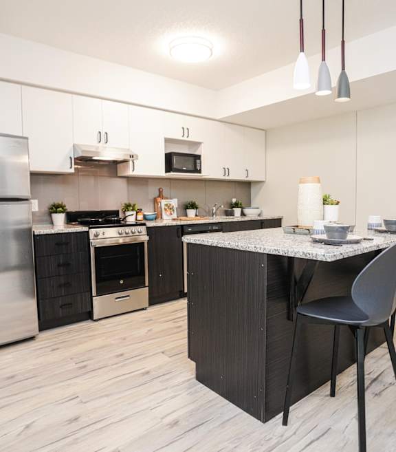 A modern kitchen with a stainless steel refrigerator and a marble top island.