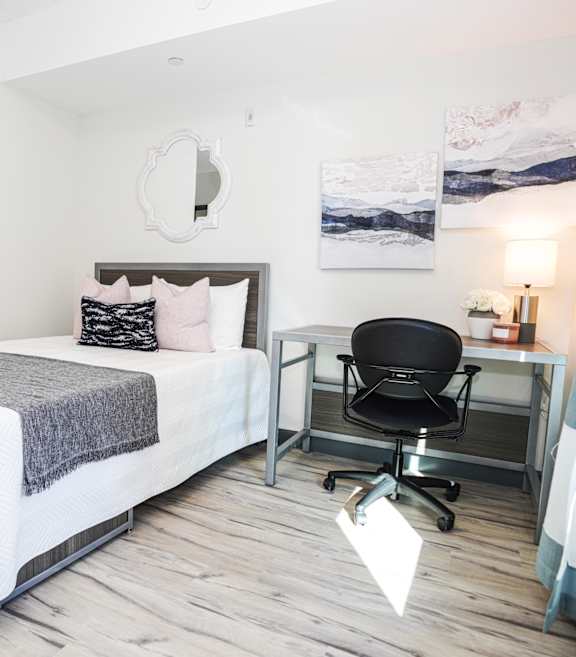 A bedroom with a bed, chair, and desk.