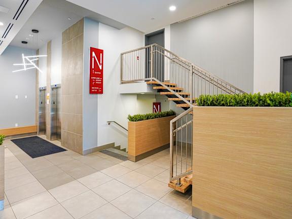 A hallway with a staircase and a sign with the letter N on it.