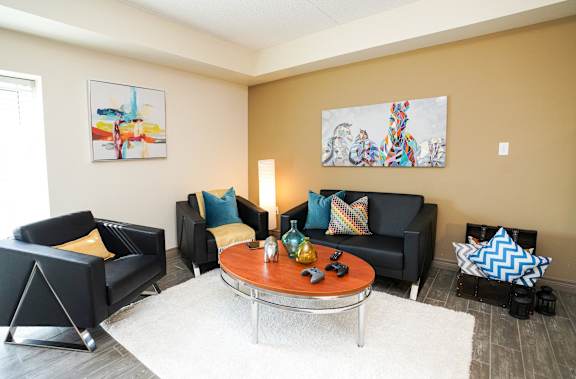 A living room with a black couch, a coffee table, and two chairs.