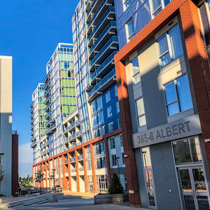 A street view of a city with buildings on both sides and a sign that reads "365-6 ALBERT".