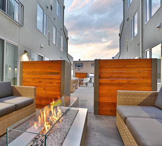 A modern patio with a fire pit and seating area.