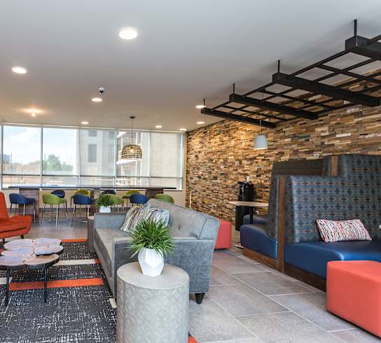 A modern living room with a stone wall and a variety of seating options.