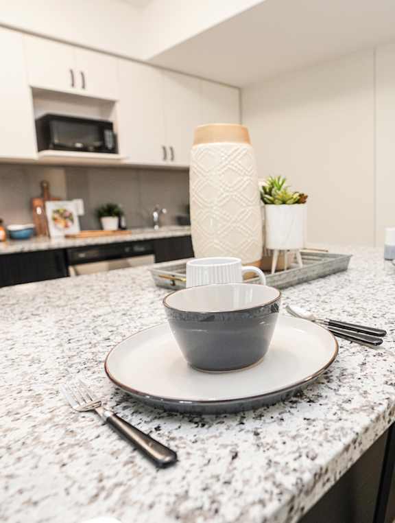 a kitchen with a marble counter top with plates and bowls on it