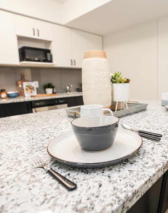 a kitchen with a marble counter top with plates and bowls on it