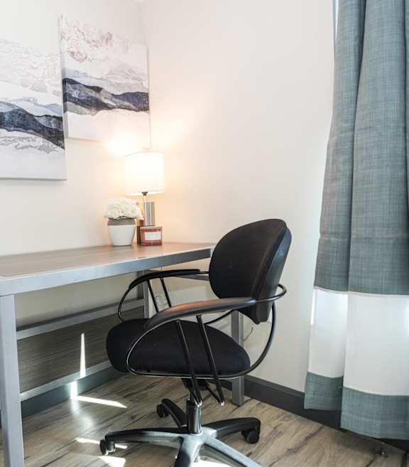a desk with a chair in a room with a bed
