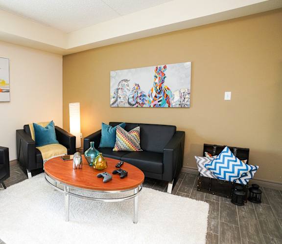A living room with a black couch, a coffee table, and two chairs.
