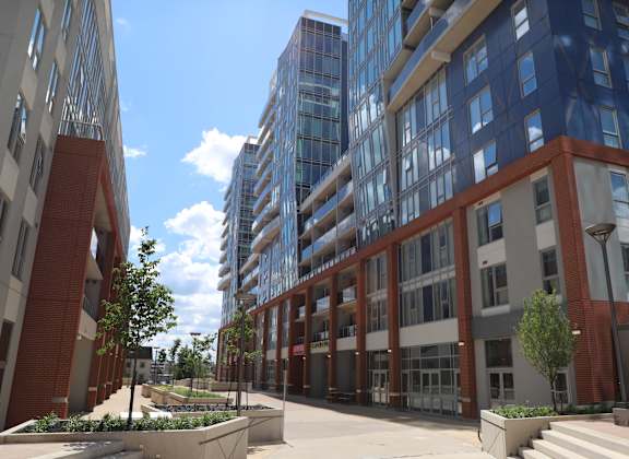 A modern building with a red brick facade and a glass facade building in the background.