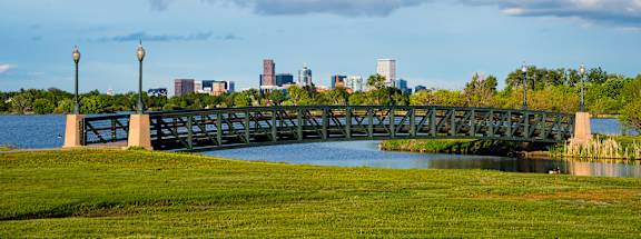 A bridge over a body of water with a city skyline in the background.