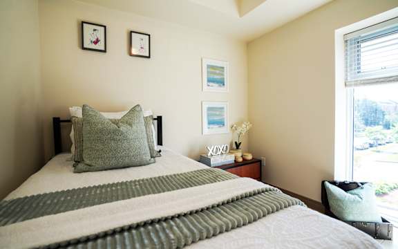 A bed with a green and white striped blanket and a green pillow is in the foreground of the image.
