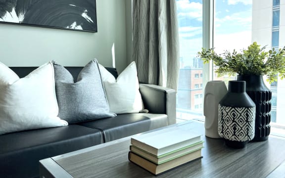 a living room with a couch and a table with books and a vase