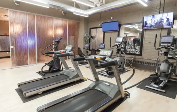 a gym with cardio equipment and a tv in a building