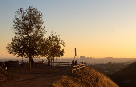 a group of people standing on a hill overlooking a city at sunset at Sunset Barrington Gardens, Los Angeles, CA