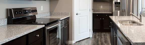 A kitchen with black cabinets and a white door.