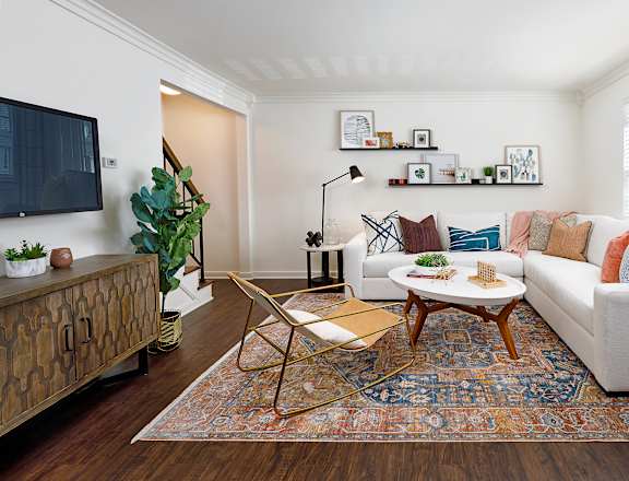 A living room with a white couch, a wooden coffee table, and a rug.