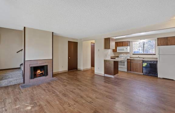A living room with a fireplace and wooden floors.