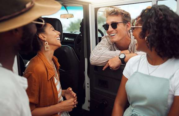 A group of people are sitting in a car, having a conversation.