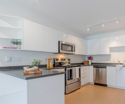 A modern kitchen with white cabinets and stainless steel appliances.