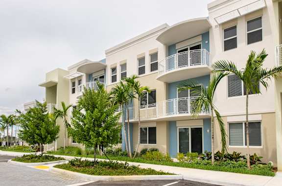 A row of modern apartment buildings with balconies and trees in front.