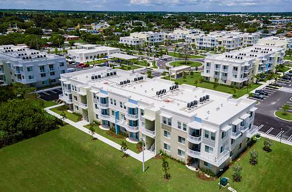 A large white apartment complex with a green lawn in front.